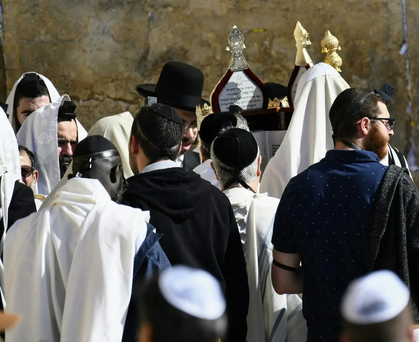 מתפללים עטופים בטליתות סביב ספר תורה ליד הכותל