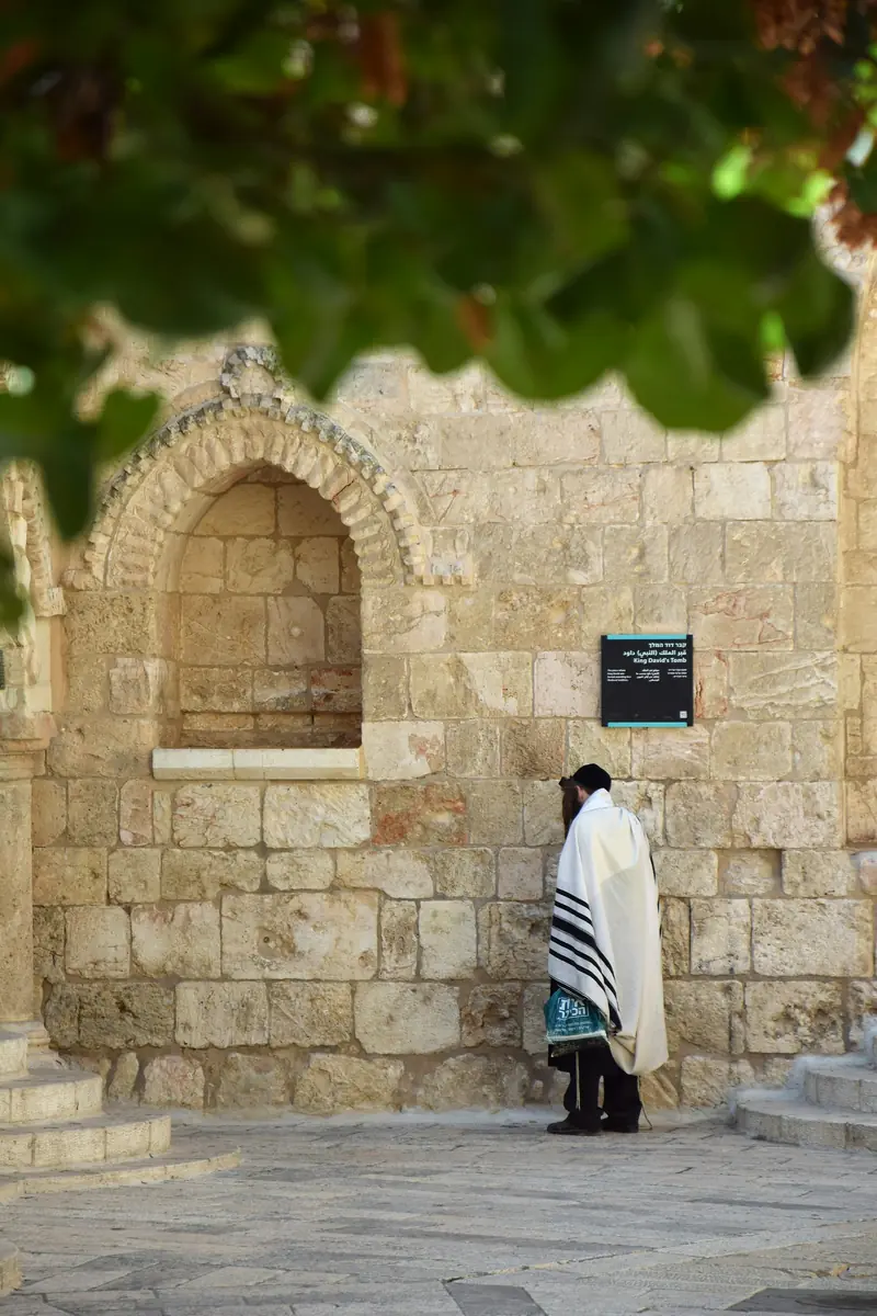 מתפלל עטוף בטלית מול אבני הכותל